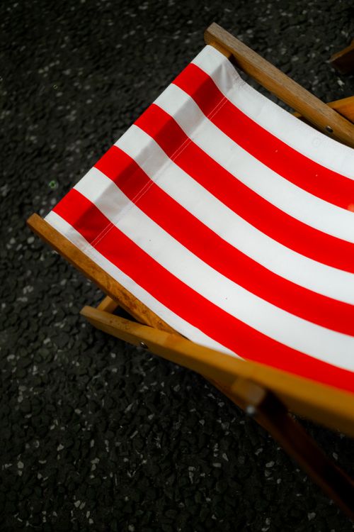 Free A red and white striped deck chair on a textured surface, captured outdoors in Dublin, Ireland. Stock Photo