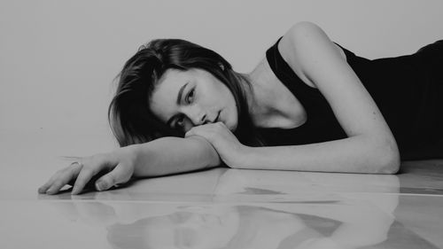 Free Black and white portrait of a woman lying on the floor, captured in a thoughtful pose. Stock Photo