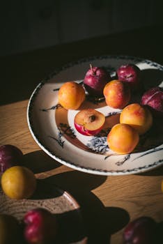 A warm, autumnal still life of fresh plums on a vintage plate in golden light.