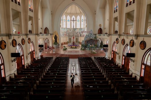 Bride and groom walking down the aisle in a large, ornate church during a wedding ceremony.