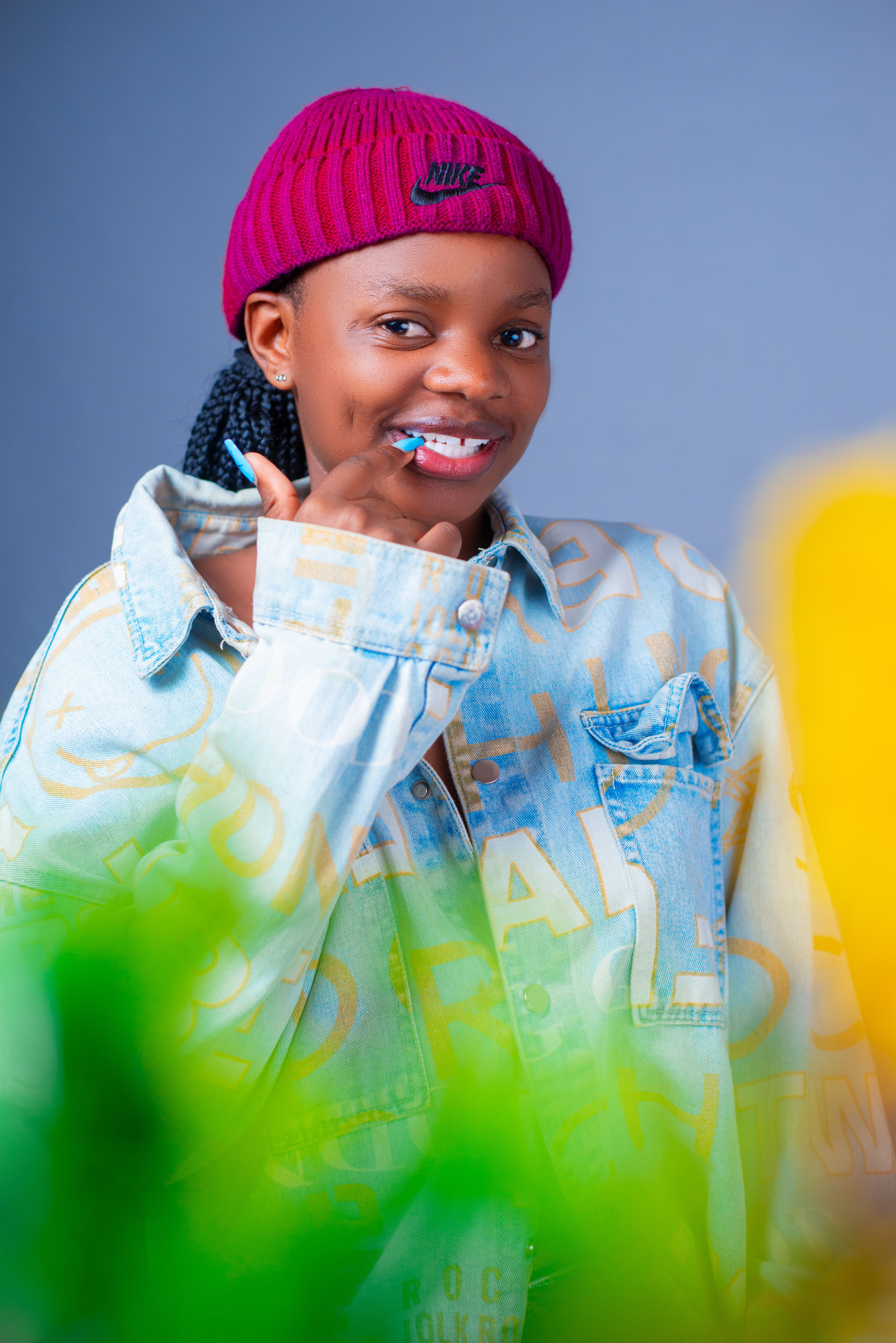 Casually dressed young woman smiling with confidence in denim and a red beanie, studio portrait.