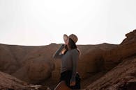 日落时分，一位戴帽子的女人在阳光明媚的沙漠峡谷中探索，拥抱冒险与自然