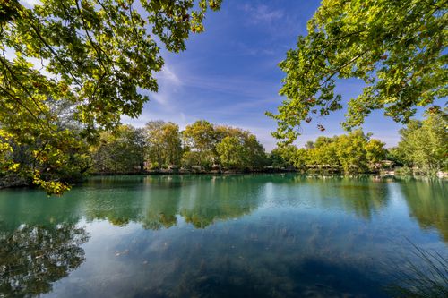 Free Serene lakeside scene with lush greenery reflecting in clear waters in Anna, Spain. Stock Photo