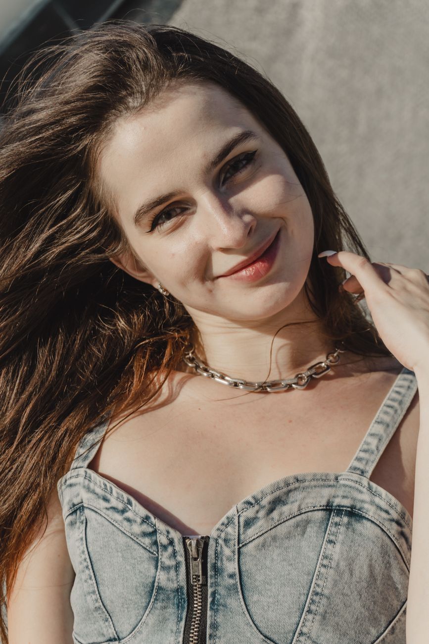 Portrait of a smiling woman in a denim top outdoors, exuding a warm and friendly vibe.