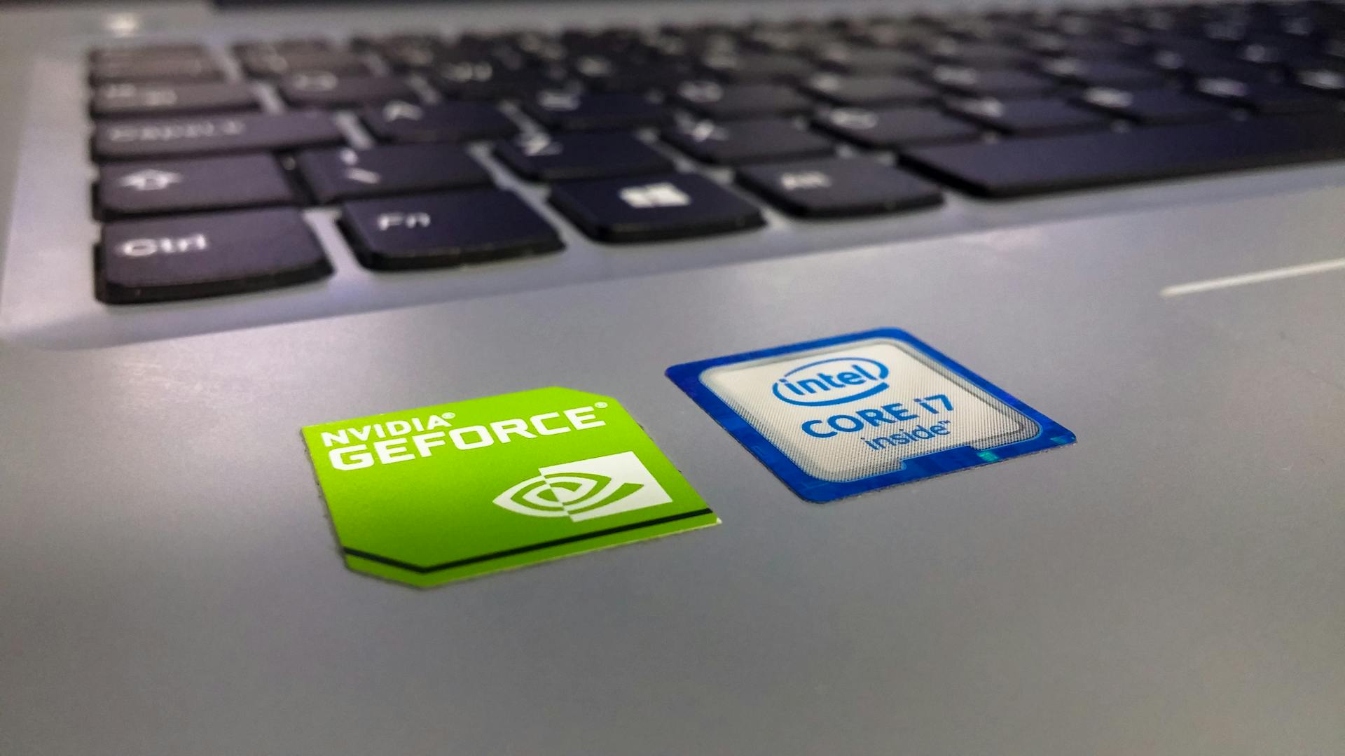 Detailed close-up of a laptop keyboard featuring Intel Core i7 and NVIDIA GeForce stickers, highlighting technology components.