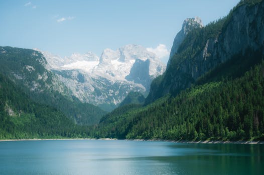 Stunning view of an alpine lake surrounded by lush forest and majestic peaks in Austria.
