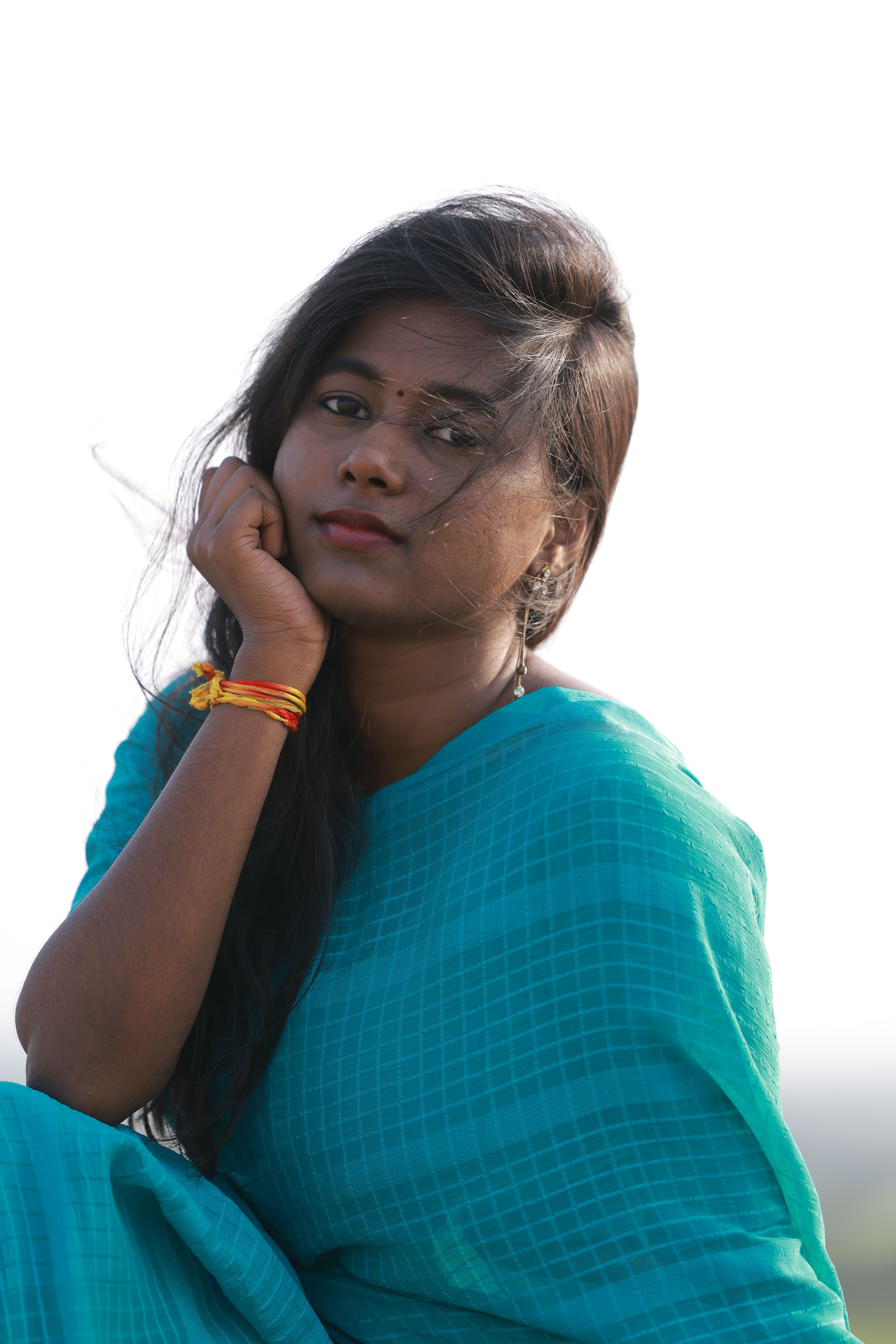 Portrait of a young woman in traditional blue attire, gazing thoughtfully outdoors.