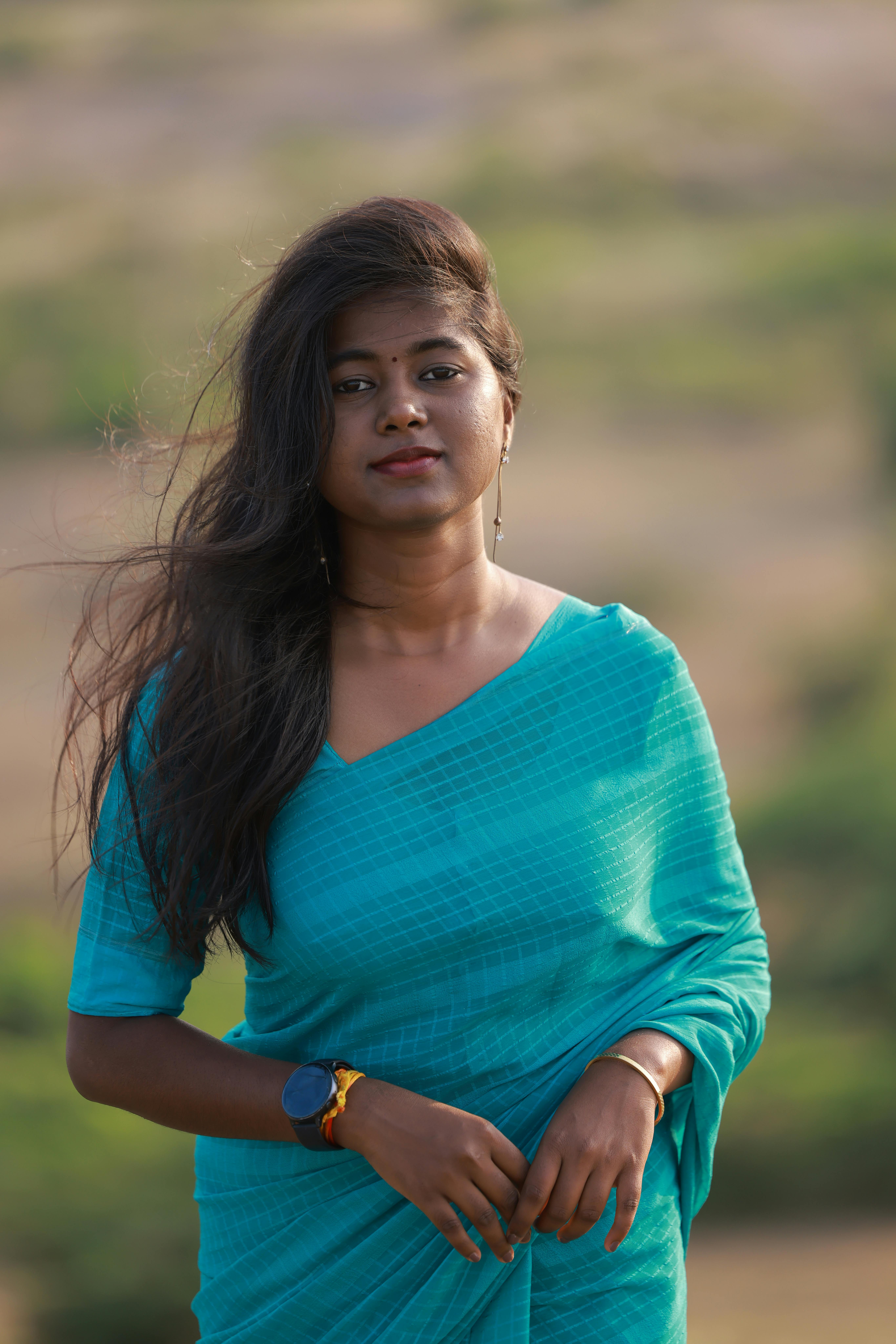 A woman in a blue outfit standing outdoors with natural background.