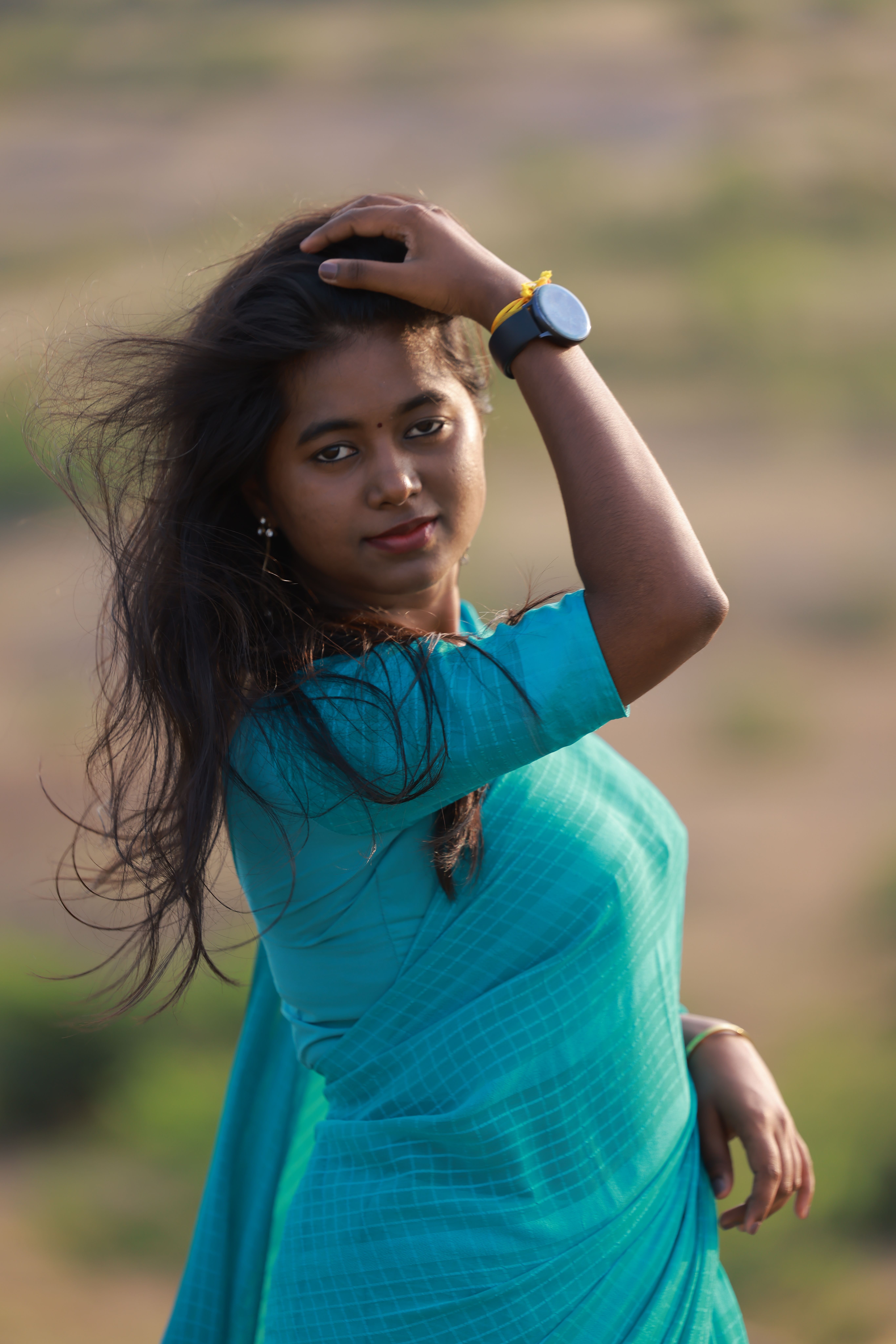 Portrait of a young woman in a blue sari enjoying the outdoors, showcasing natural elegance.