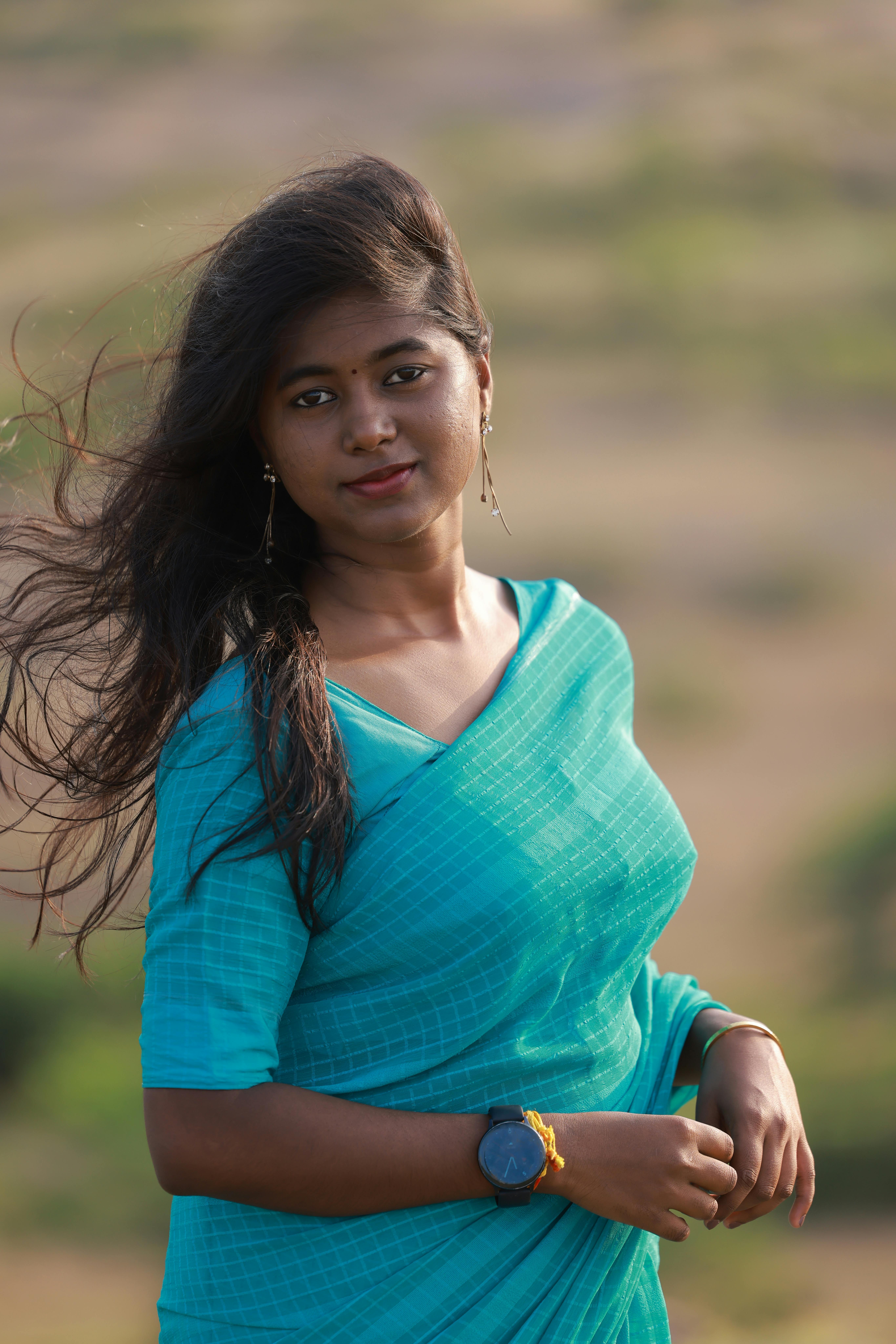 Portrait of a young woman wearing a blue sari, standing gracefully outdoors.