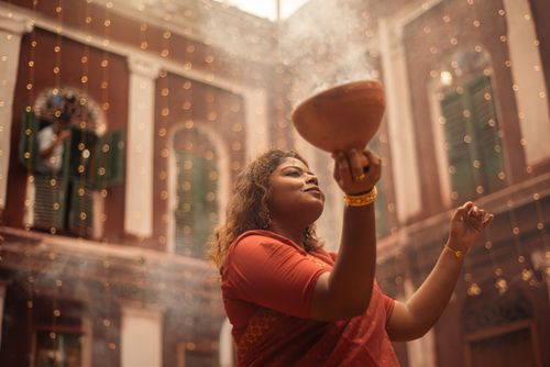 Free A woman in traditional attire performing a ritual in a decorated festive setting. Stock Photo