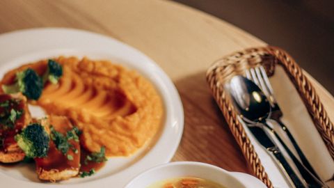 Warm vegetable soup and mashed sweet potatoes with broccoli, perfect for cozy dining.