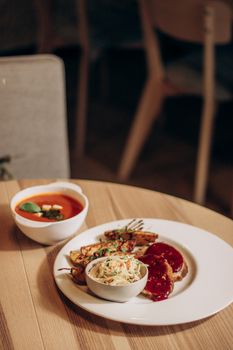 A cozy dinner setting featuring tomato soup, grilled chicken, and coleslaw on a wooden table.