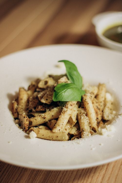 Free Close-up of creamy pasta topped with pesto and fresh basil, perfect for Italian cuisine lovers. Stock Photo
