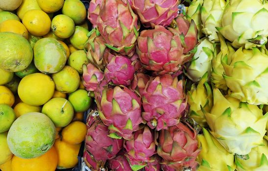Colorful display of dragon fruits and citrus at a market, showing tropical freshness., free online jigsaw puzzle on JigsawPuzzlesFreeOnline.org