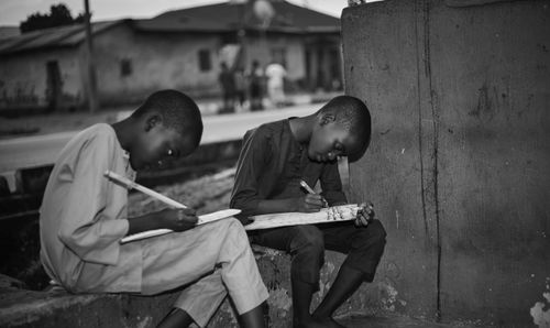 Free Two children focused on studying outside. Captured in monochrome. Stock Photo