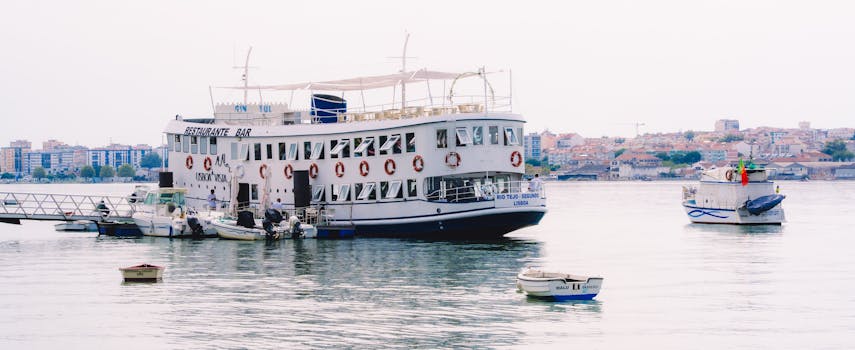 Floating restaurant ferry moored on Tagus River in Lisbon with city skyline backdrop.