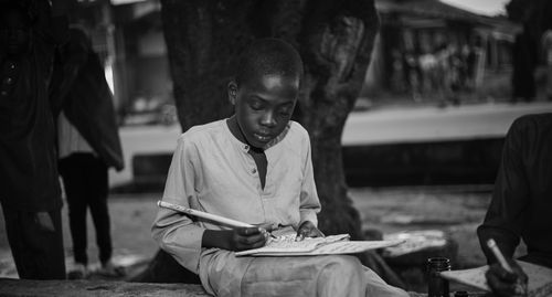 Free A young boy immersed in painting outdoors, captured in a striking black and white photo. Stock Photo