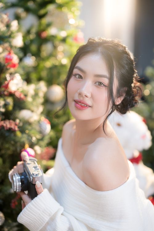 Free Joyful woman with a camera by a Christmas tree, embracing holiday spirit. Stock Photo