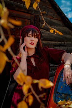 Woman in autumn fashion leaning on vintage car amidst fall foliage in Breckenridge.