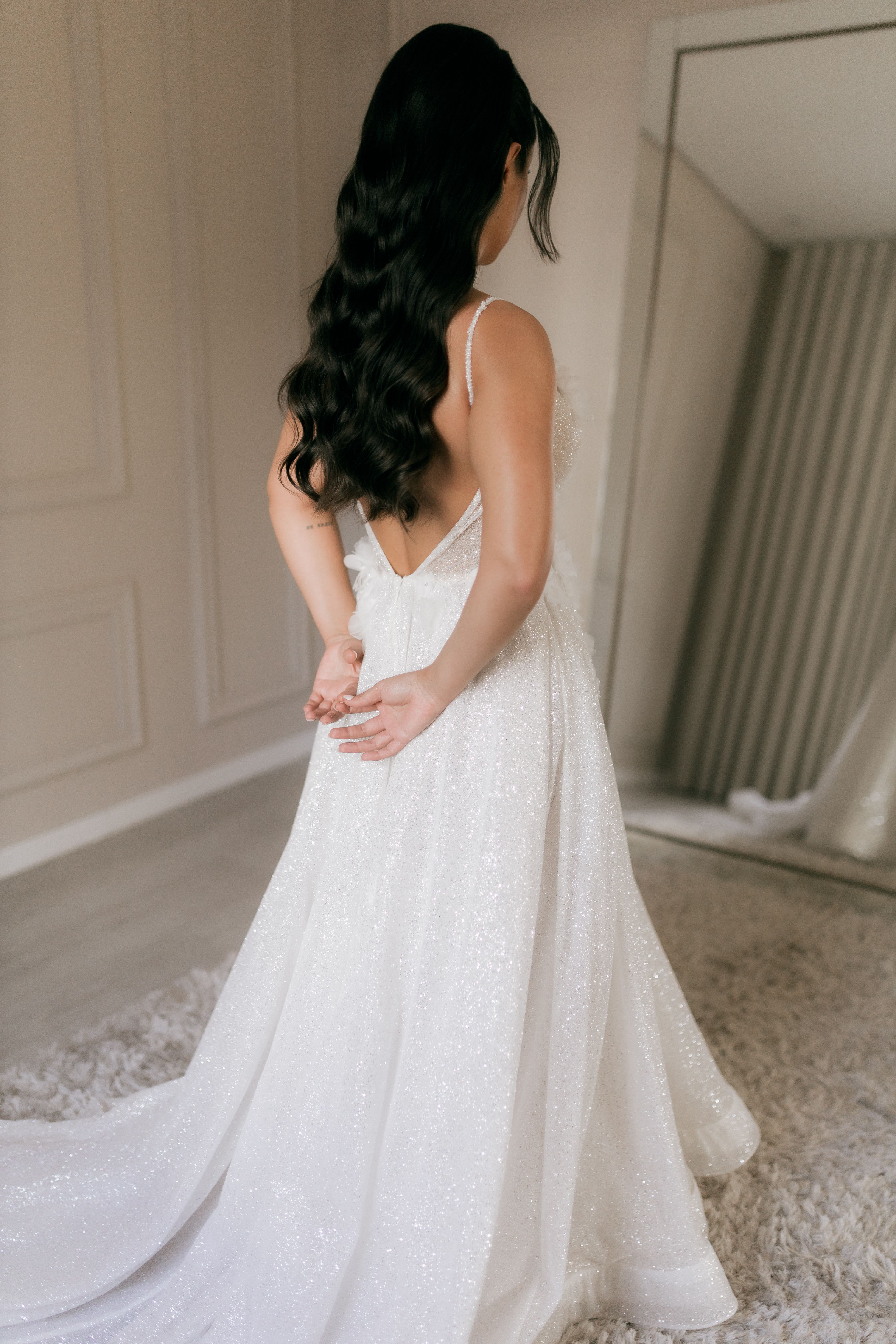 Bride elegantly posed in a luxurious white wedding dress indoors.