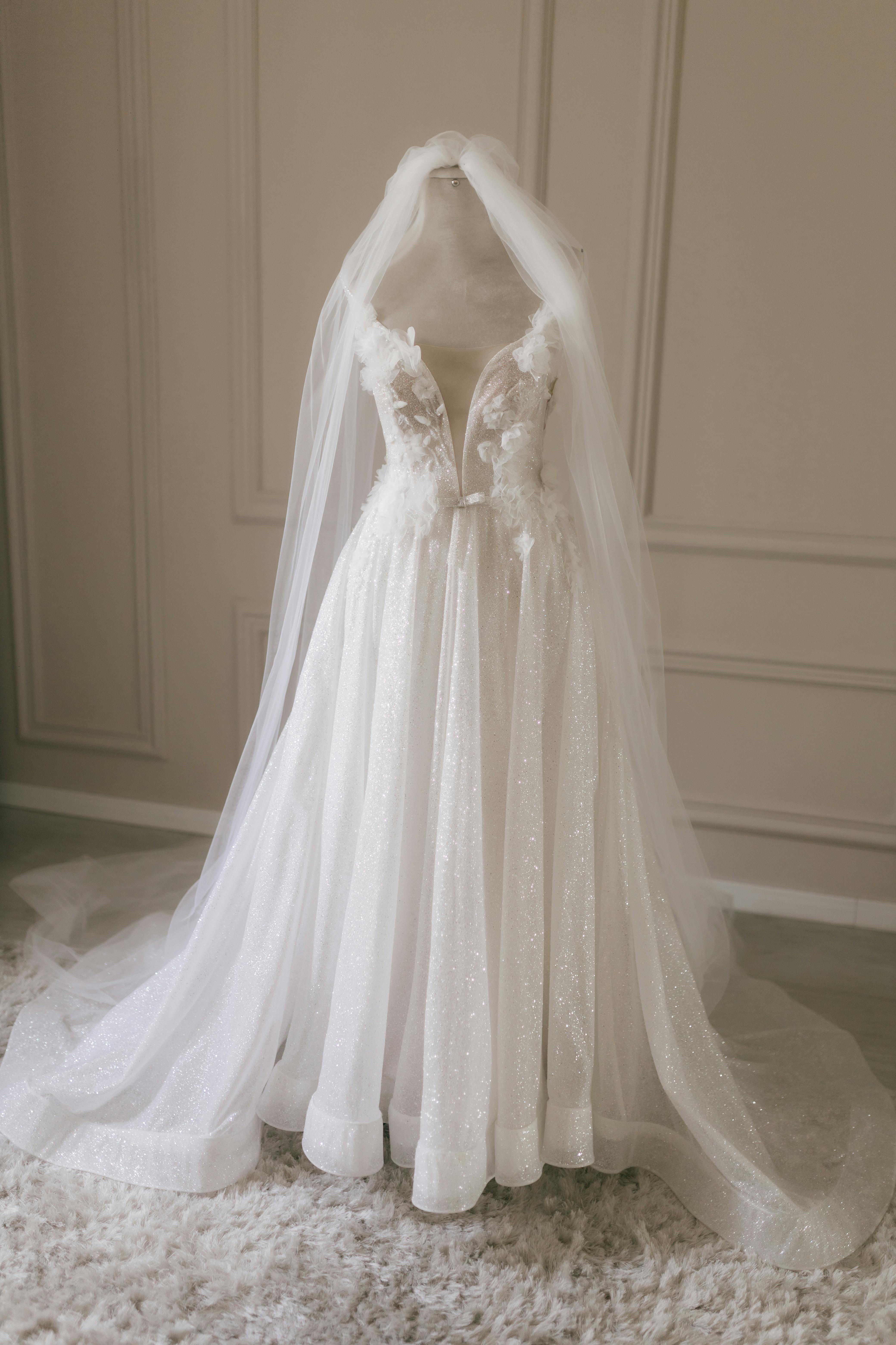 Sophisticated white wedding gown displayed on mannequin in soft light.
