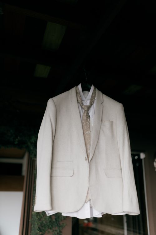 Free A cream suit with tie and waistcoat hanging in a dark room. Stock Photo