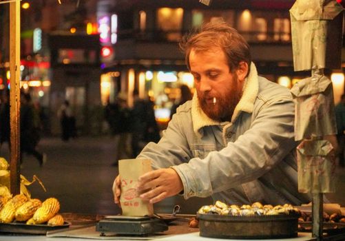 A street vendor in Istanbul serves roasted chestnuts at night, capturing the vibrant city vibe.