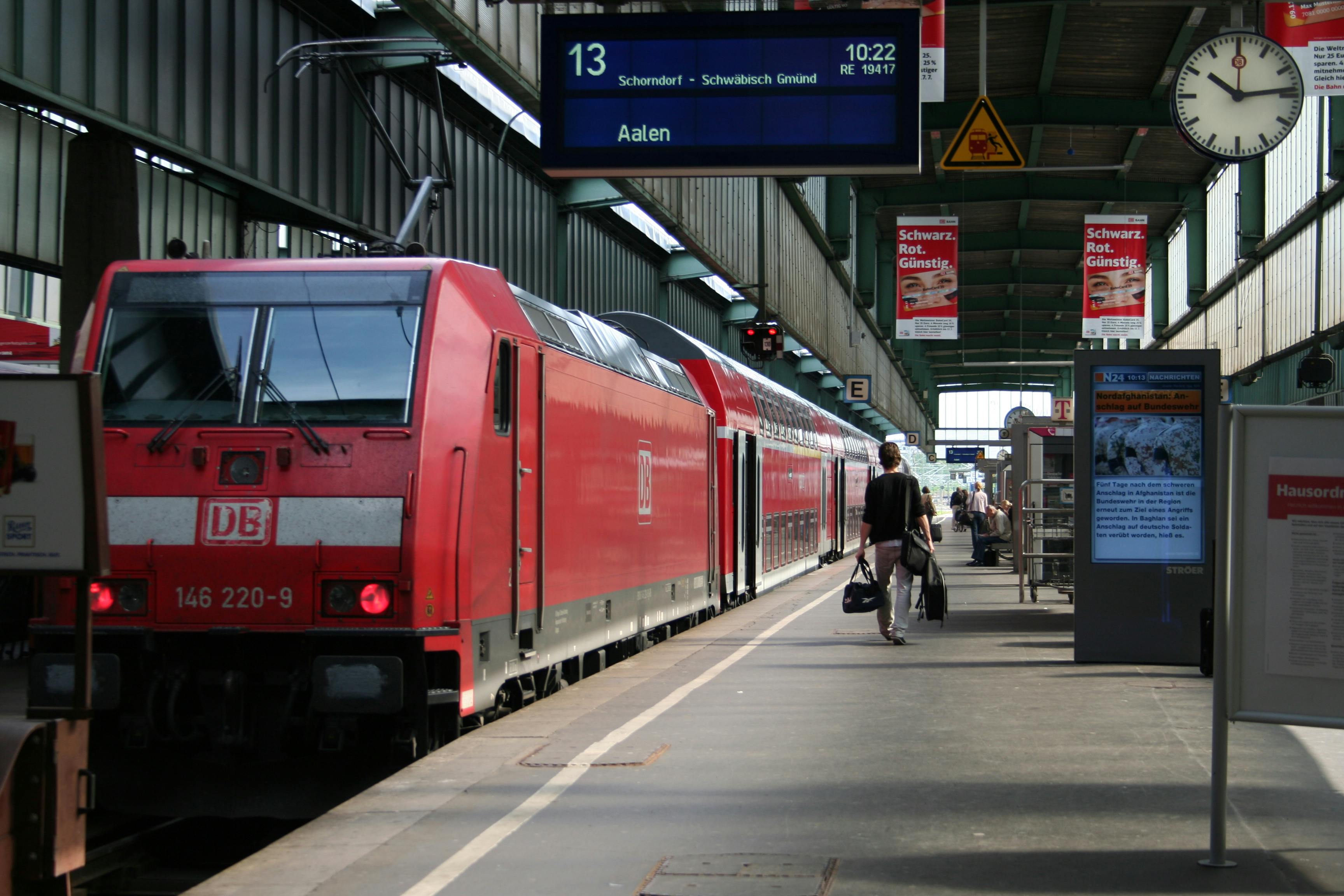 A red DB train at Aalen station platform with passengers preparing to board.