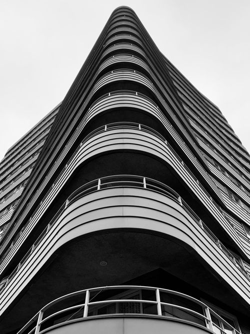 Free Black and white photo of a modern skyscraper in Amsterdam, showcasing sleek lines and curves. Stock Photo