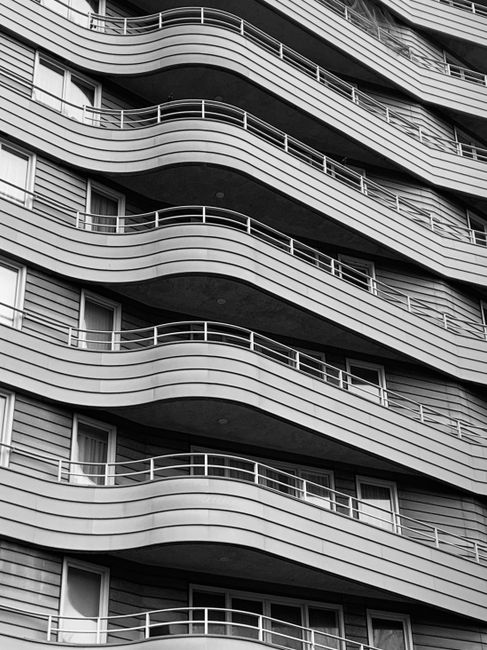Black and white photo of a modern, wavy building facade in Amsterdam.