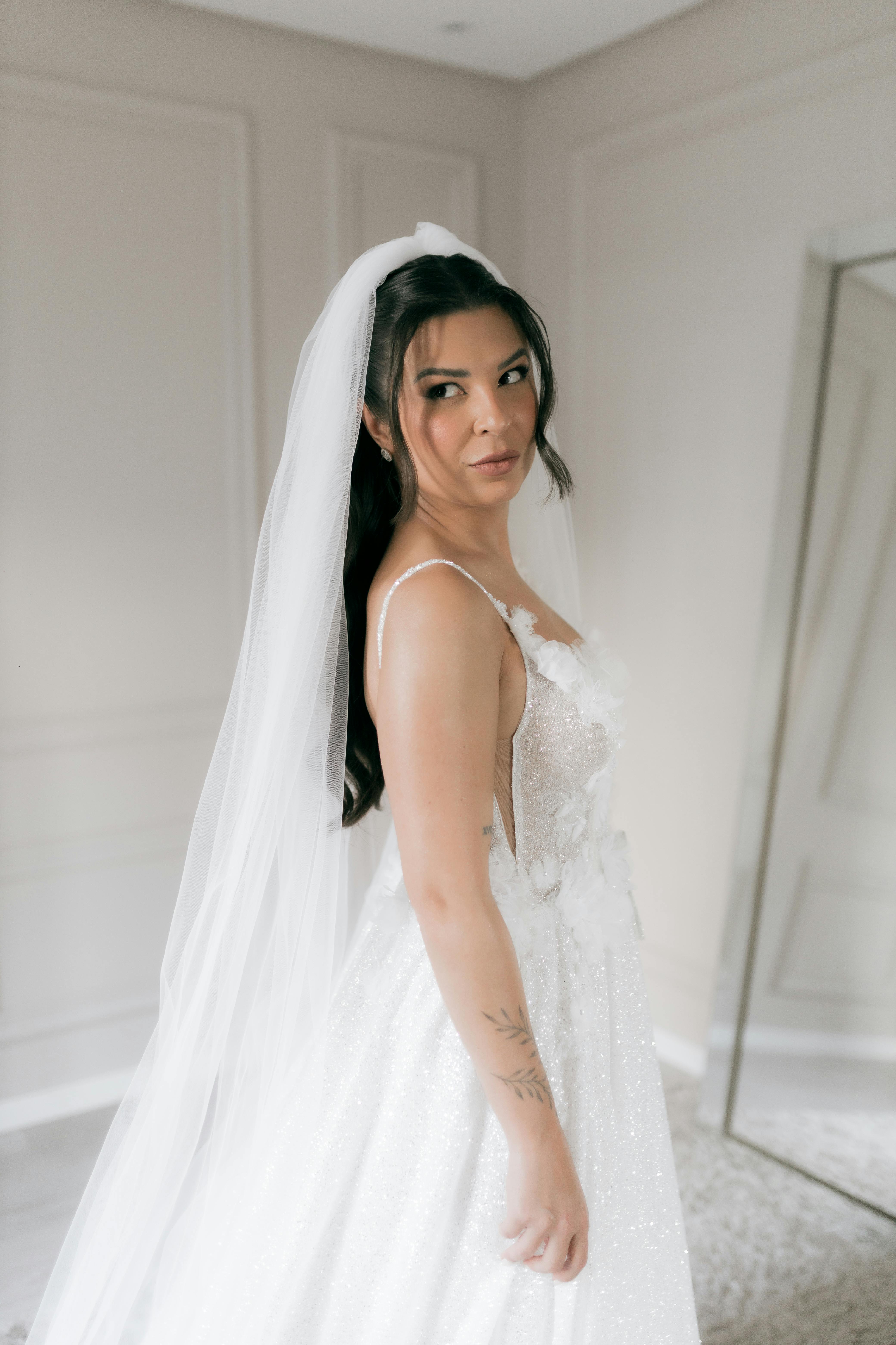 Portrait of a bride in a sparkling white gown with a veil in an elegant indoor setting.