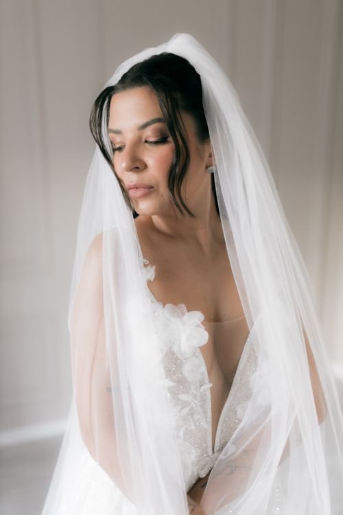Free A beautiful bride poses gracefully in an elegant white wedding dress and veil. Stock Photo