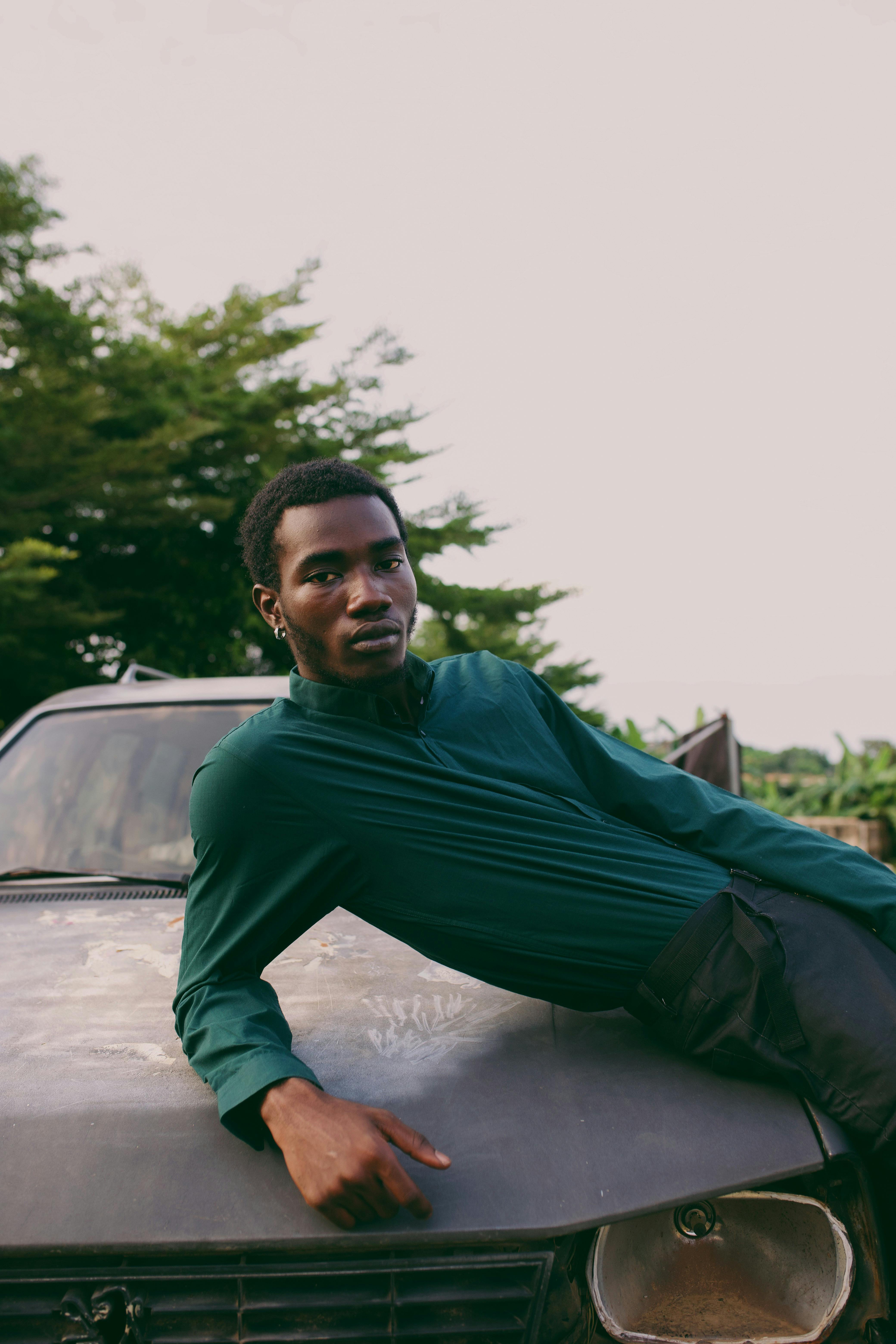 Portrait of a young man lounging on a car in a natural setting, Nigeria.
