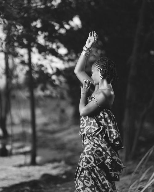 Free Graceful woman in patterned dress with raised arms in a serene outdoor setting. Stock Photo