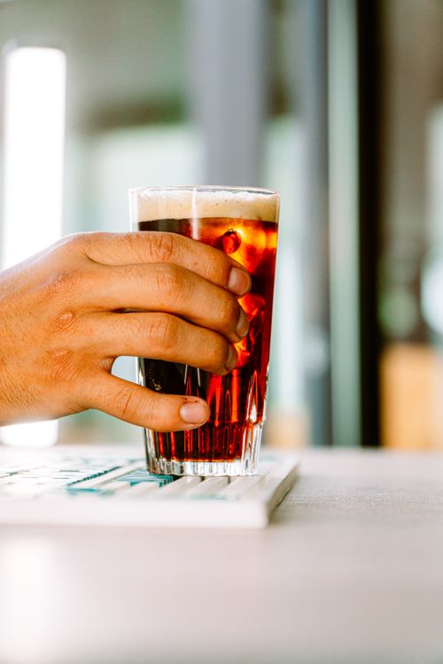 Free Close-up of a hand holding a glass of fernet in a cozy Buenos Aires bar. Stock Photo