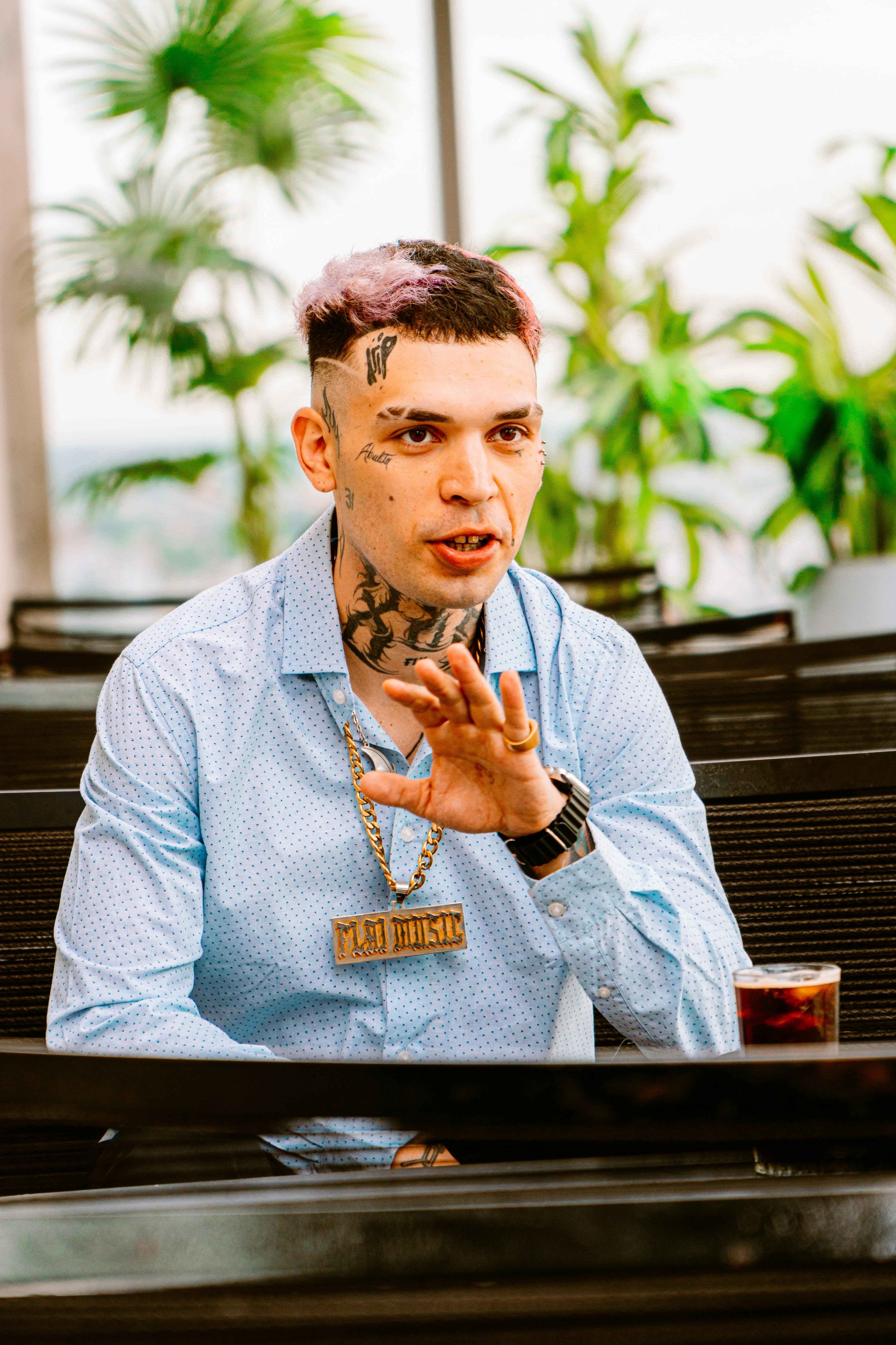 Tattooed man enjoying a drink at an outdoor café in Buenos Aires, Argentina.