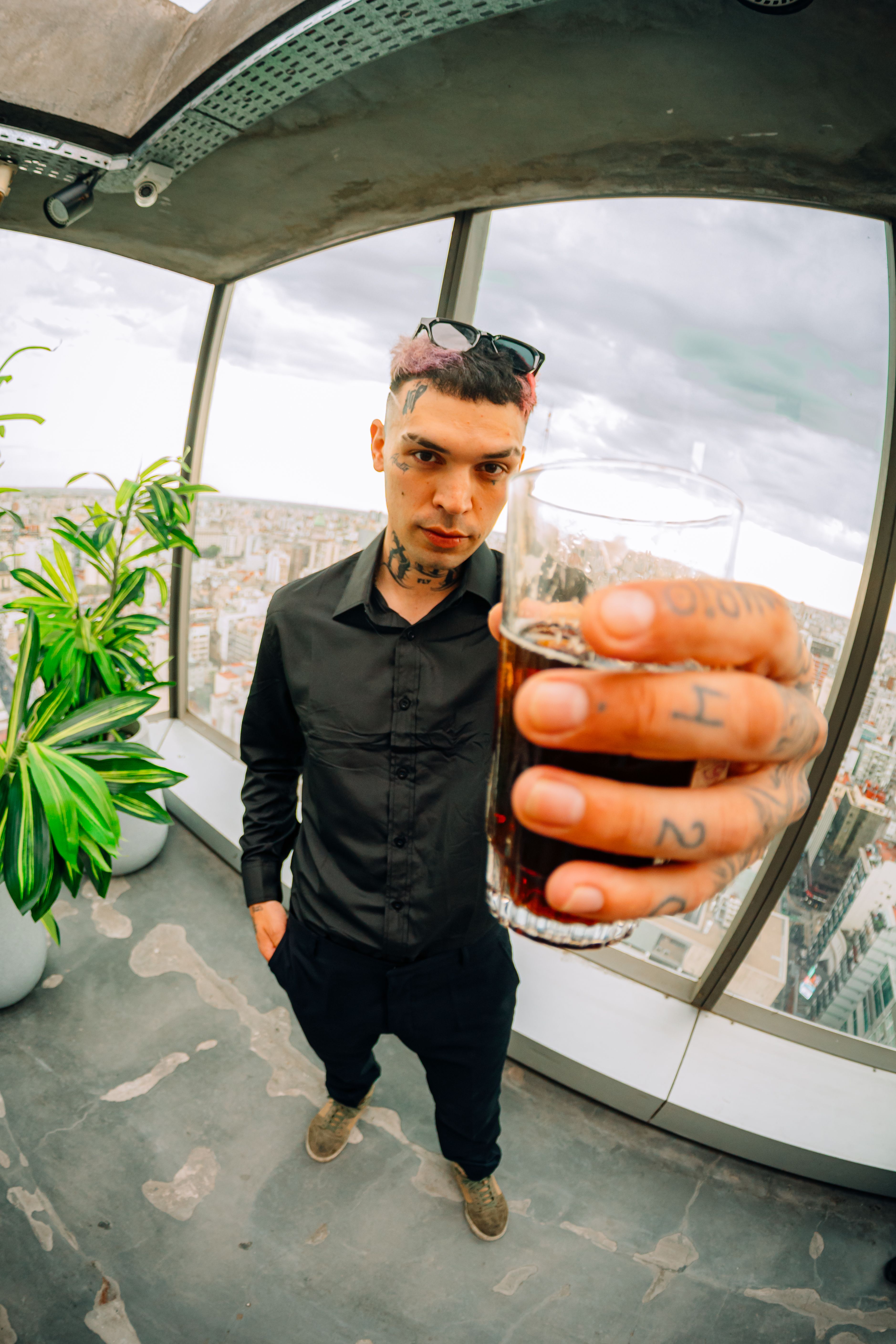 A young man offers a drink in a stylish rooftop setting overlooking Buenos Aires, Argentina.