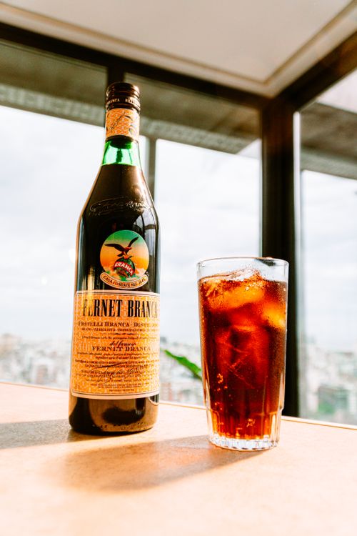 Free Fernet Branca bottle and glass in a Buenos Aires cafe with city view. Stock Photo