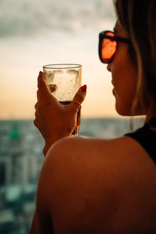 Free Woman holding a glass with a city view during sunset in Buenos Aires. Stock Photo