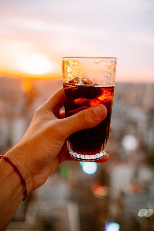 Free A hand holding a glass of fernet during a sunset in Buenos Aires, Argentina. Stock Photo