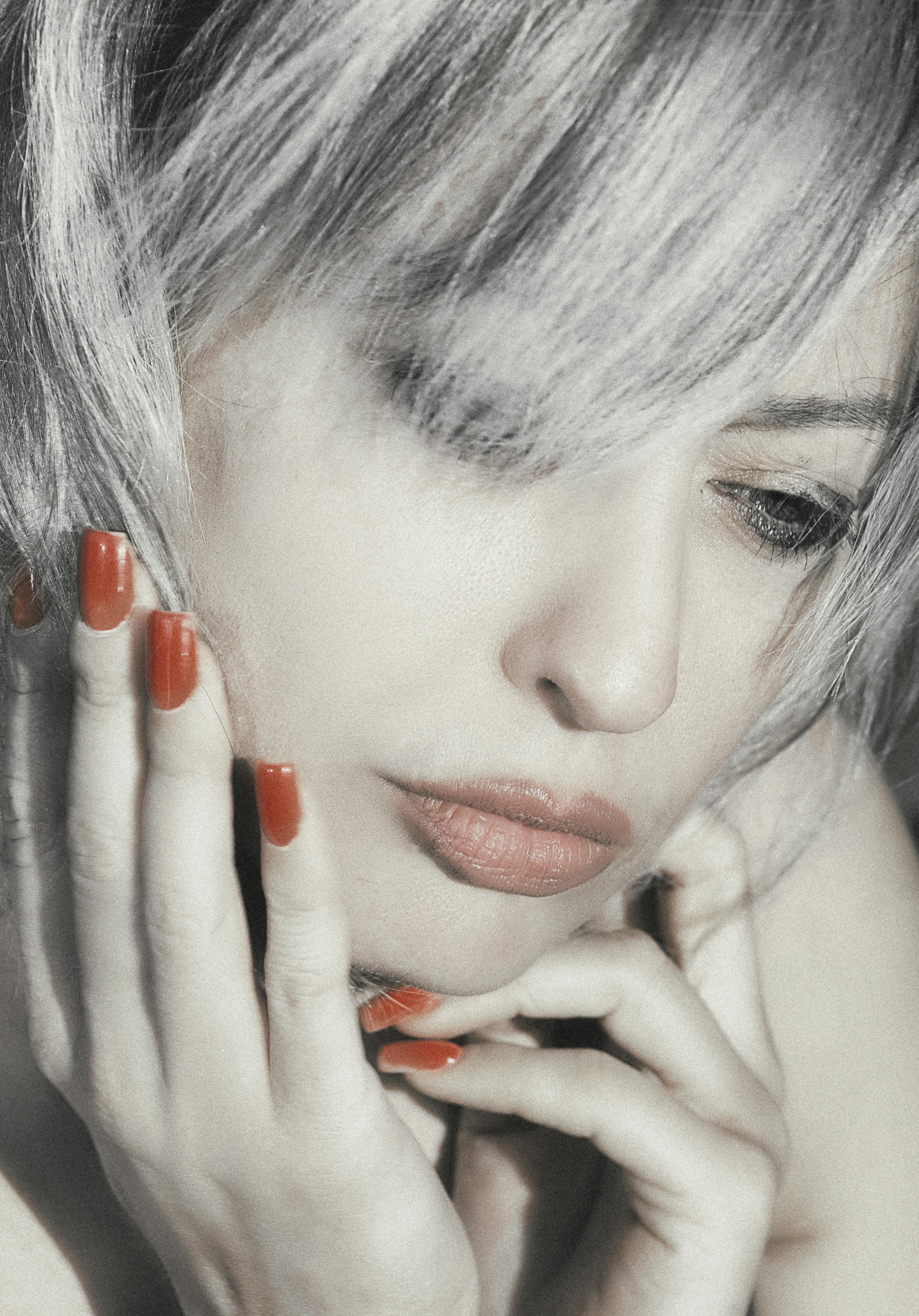 Close-up of a pensive woman with red nails, capturing deep emotion.