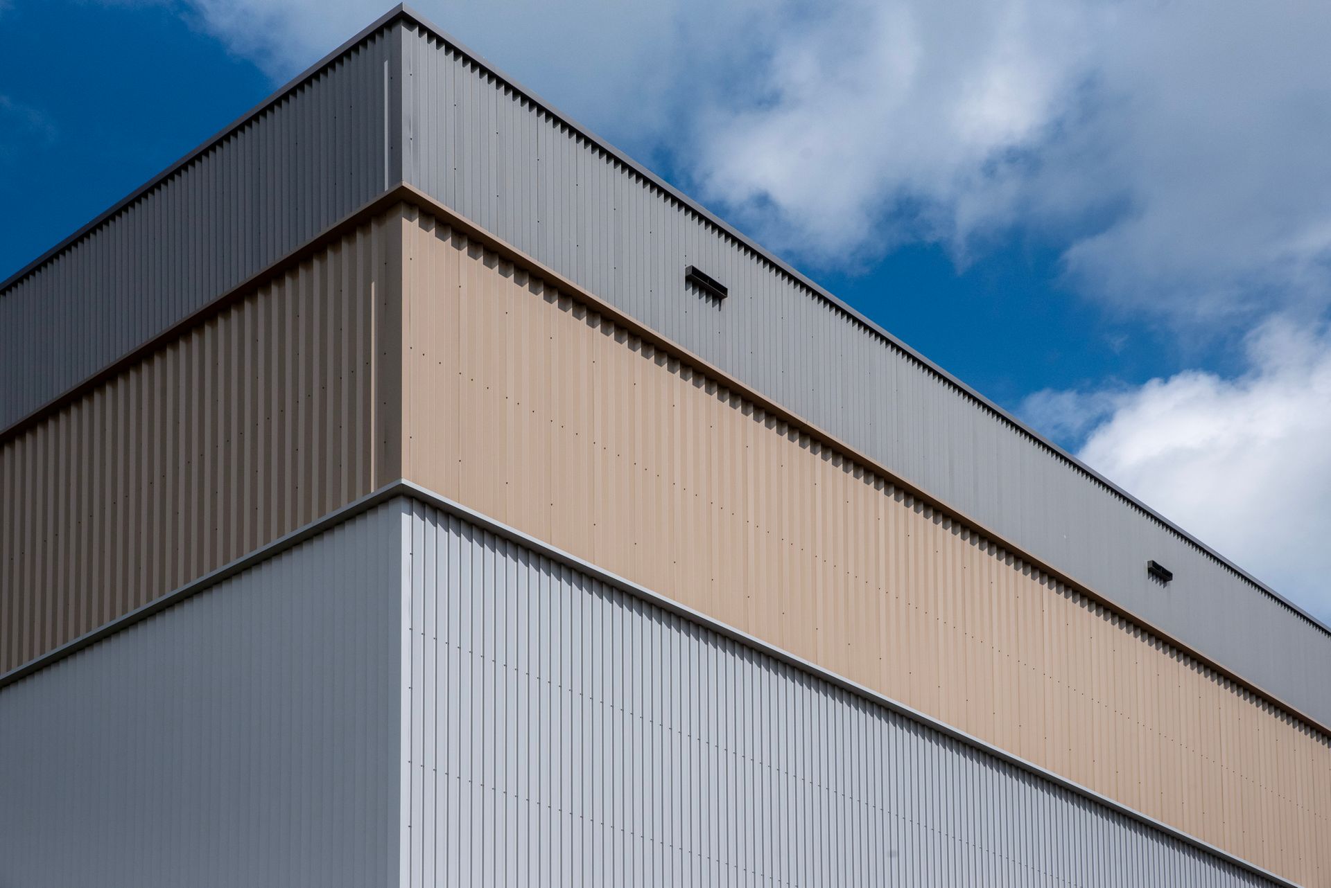 Detailed view of a modern industrial building's corner against a blue sky in Zoetermeer, Netherlands.