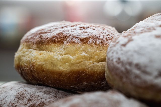 Sugar-dusted filled doughnuts stacked on a tray — photo by Patrick on Pexels