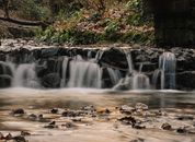 Spectacular long exposure shot of wonderful low waterfall in quiet forest in autumn