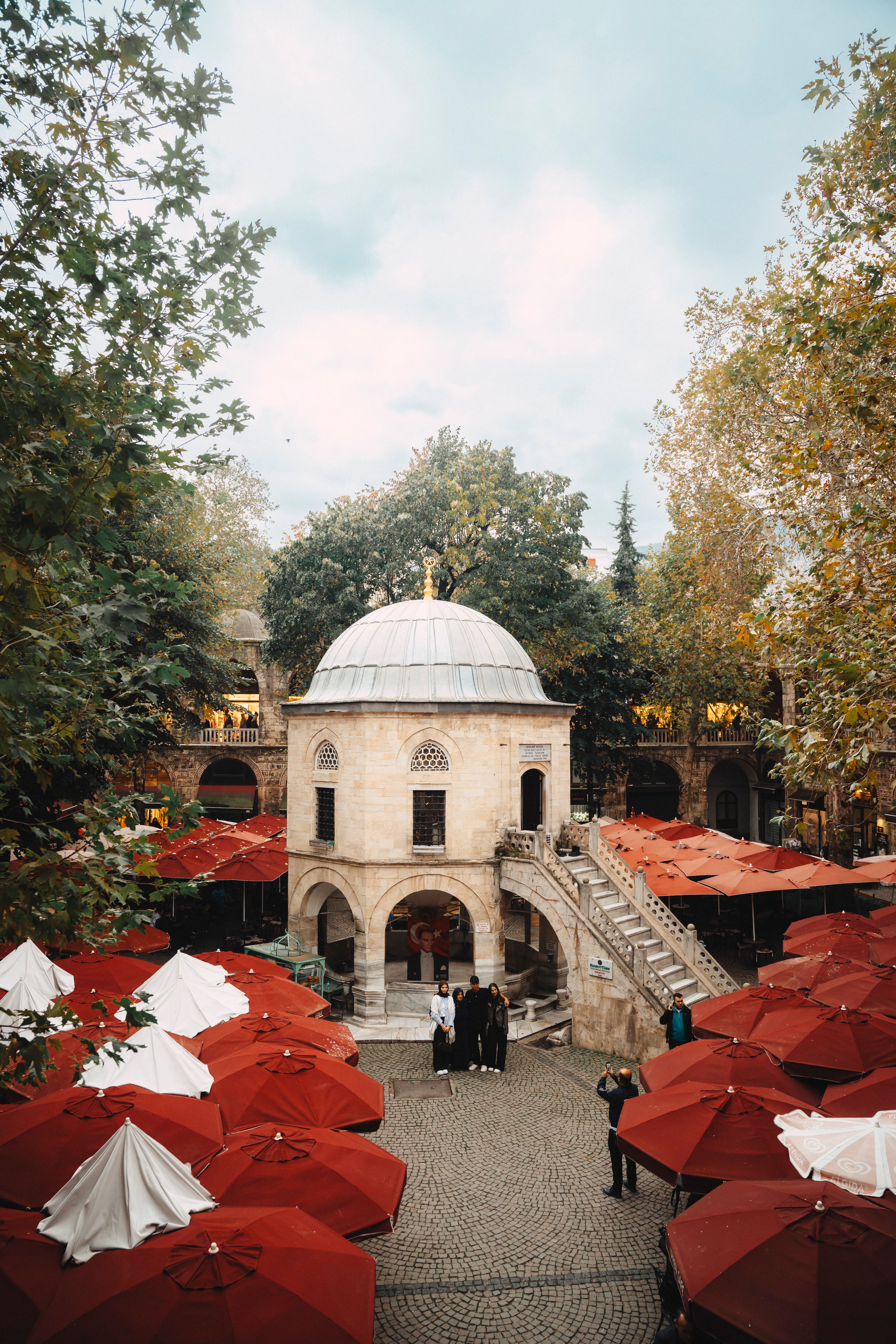 Stunning view of Ottoman architecture surrounded by vibrant red umbrellas in a lively courtyard.