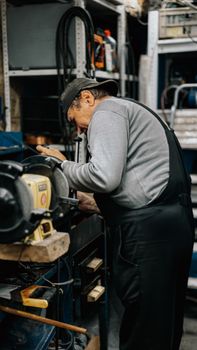 Experienced craftsman working with grinding machine in a busy workshop.