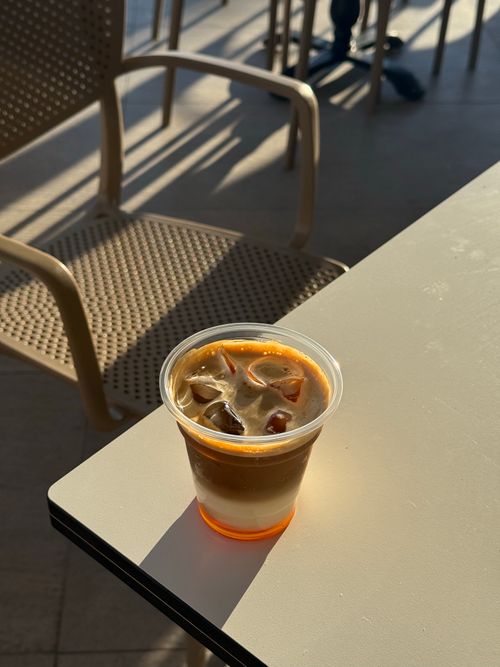 Free Refreshing iced coffee in a plastic cup on a sunlit table inside a modern cafe. Stock Photo
