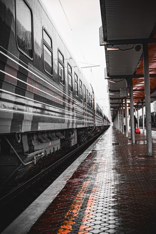 Free A rainy day at an urban railway platform featuring a sleek train and reflective wet ground. Stock Photo