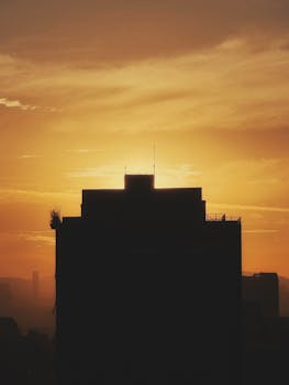Dramatic silhouette of a building at sunset with a vibrant golden sky